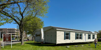 Michigan Hits New Strides in Bringing ‘Homes to the People’ outdoor park public display of manufactured home set up green grass blue sky michigan public park