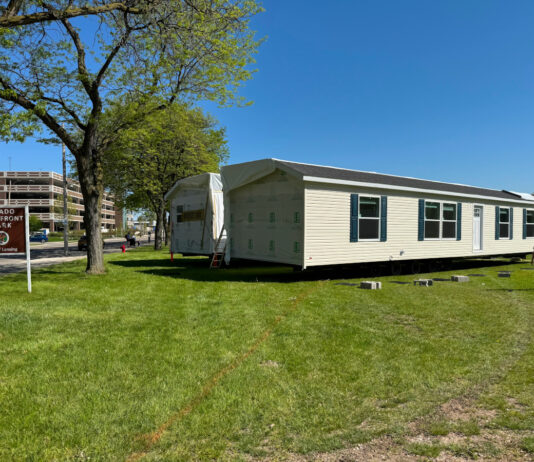 Michigan Hits New Strides in Bringing ‘Homes to the People’ outdoor park public display of manufactured home set up green grass blue sky michigan public park